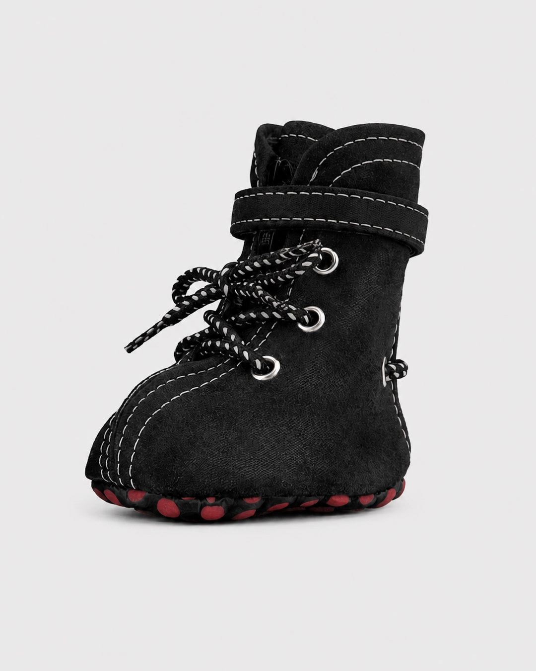 Black dog boots with red soles on a light gray background
