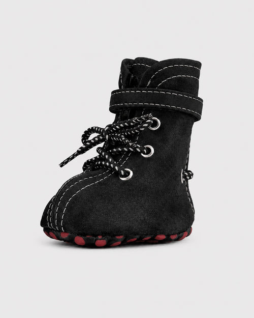 Black dog boots with red soles on a light gray background
