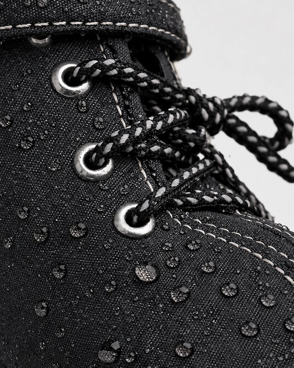 Close-up of a black boot with water droplets on a white background