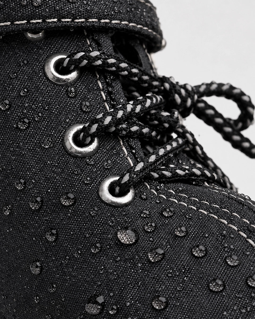Close-up of a black boot with water droplets on a white background