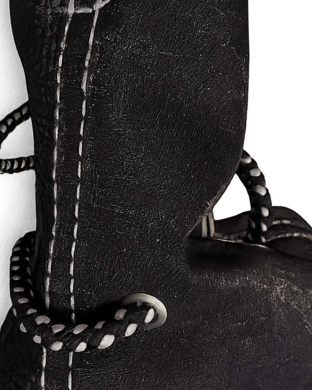 Close-up of a black leather boot with white stitching on a white background